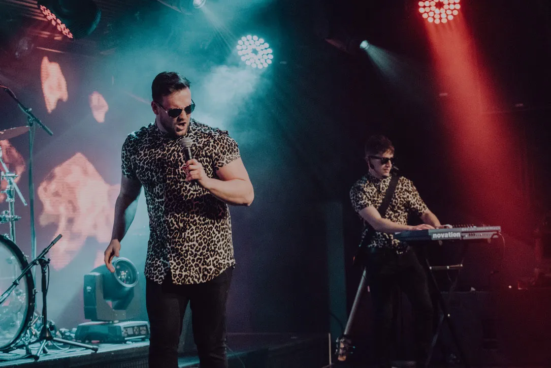 Lead singer performing live with spotlight background