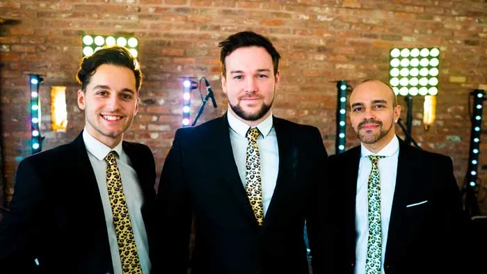 Three band members of The Vegas Hooligans smiling in formal suits